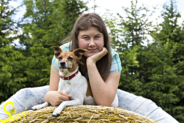 Die 13 jährige Tina mit ihrem Hund Kessi, auf einem großen Strohballen.